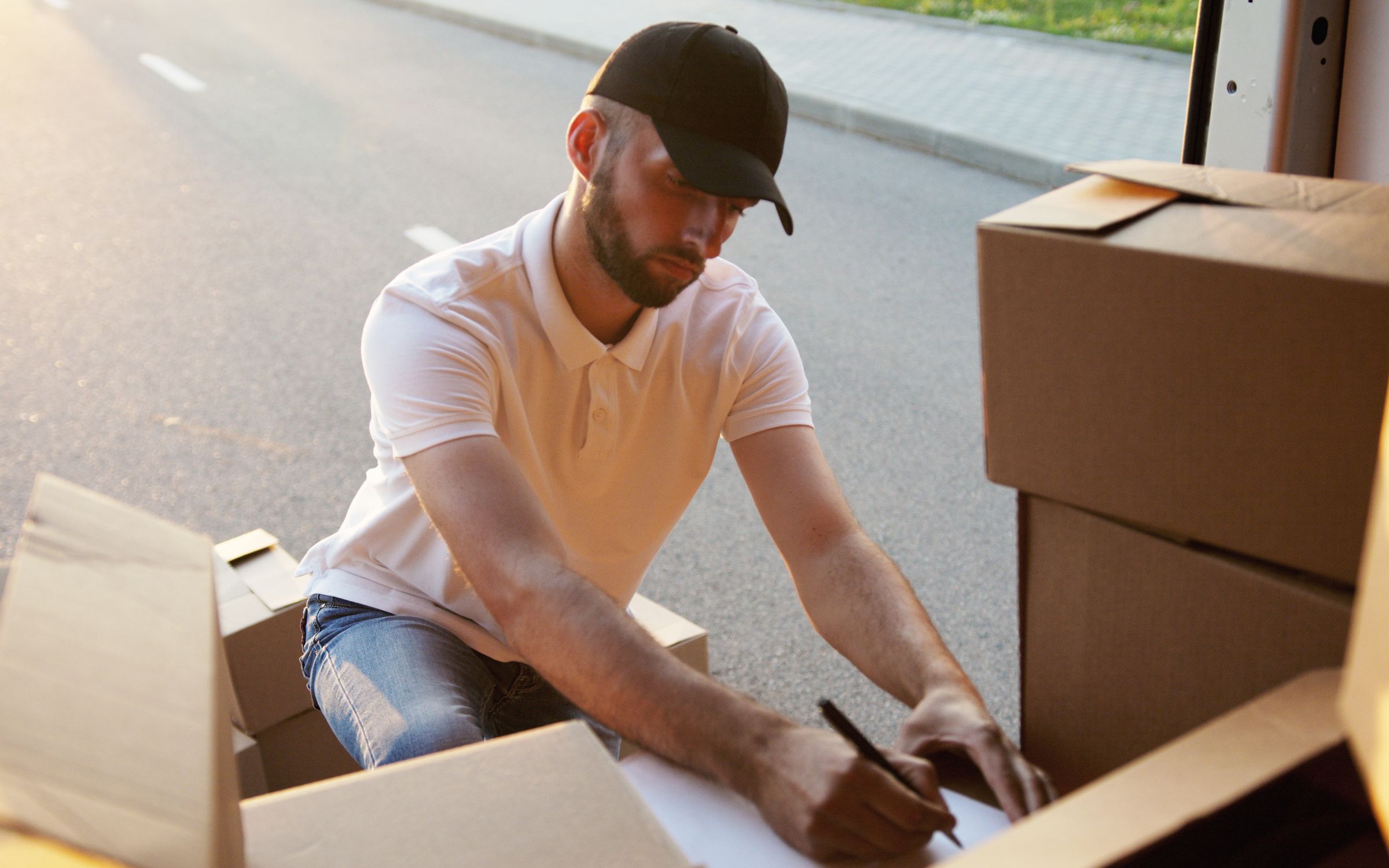 A courier scanning and signing for parcels beside a delivery van