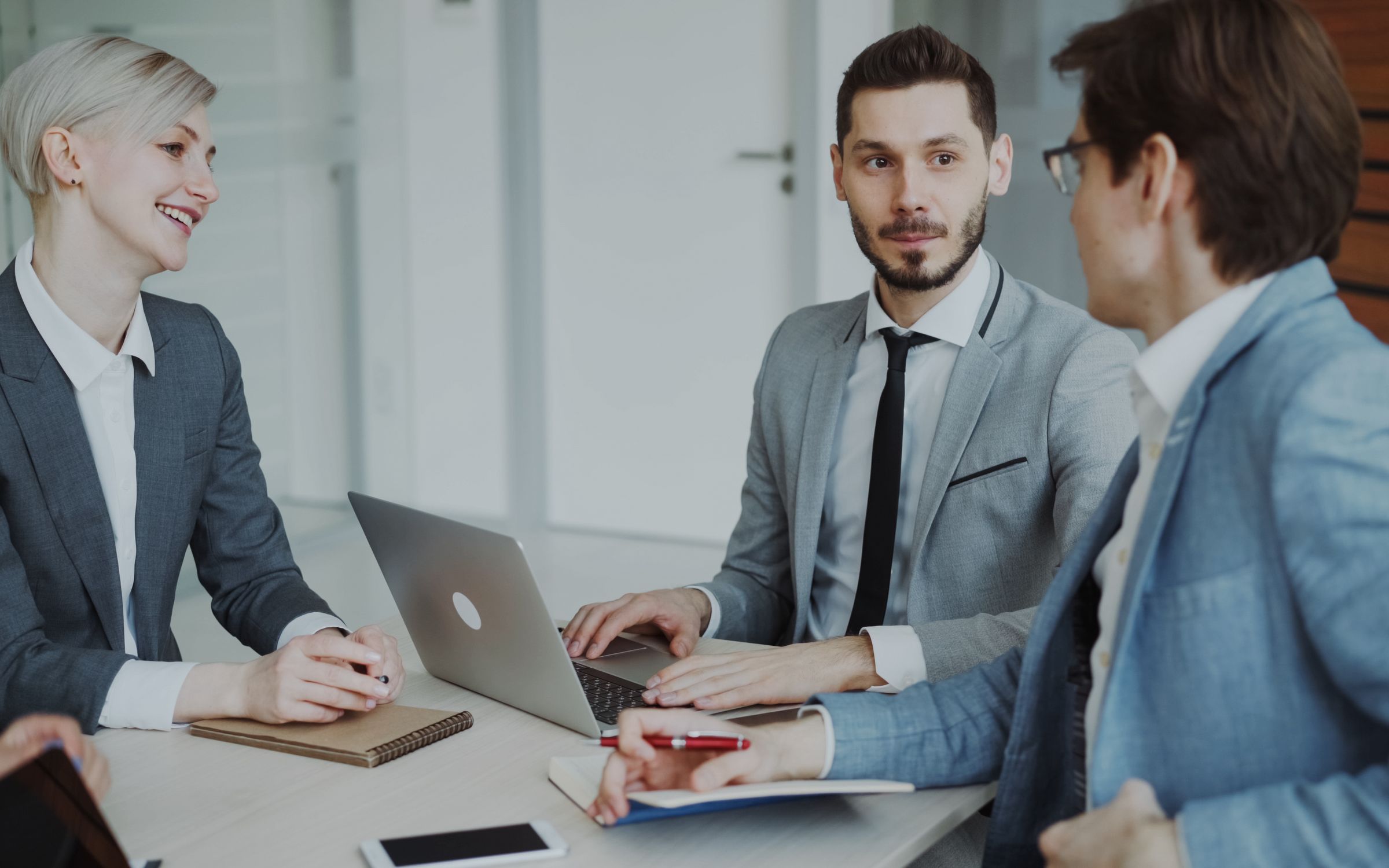 Business consultants in a meeting reviewing a project on a laptop