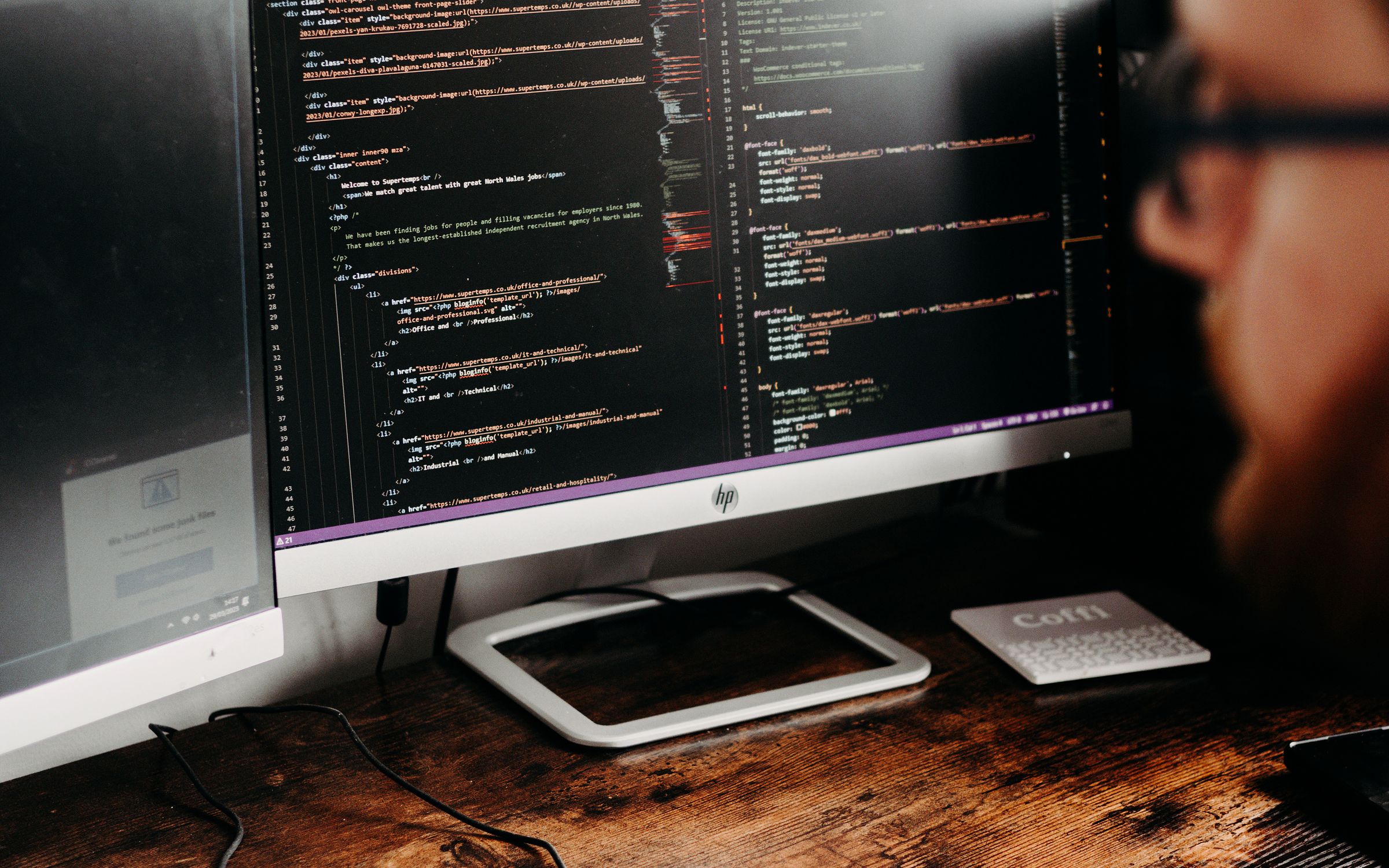 A developer working on application source code across desktop monitors